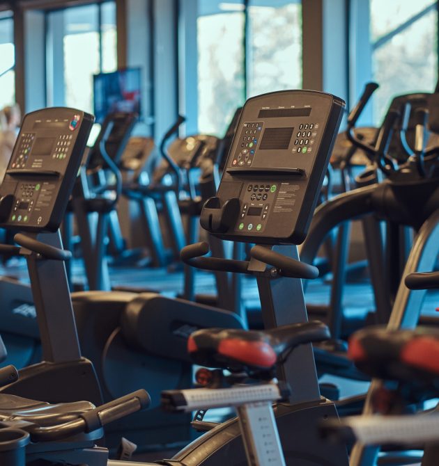 Modern equipment in a gym indoors. Interior of fitness hall with fitness bicycles.
